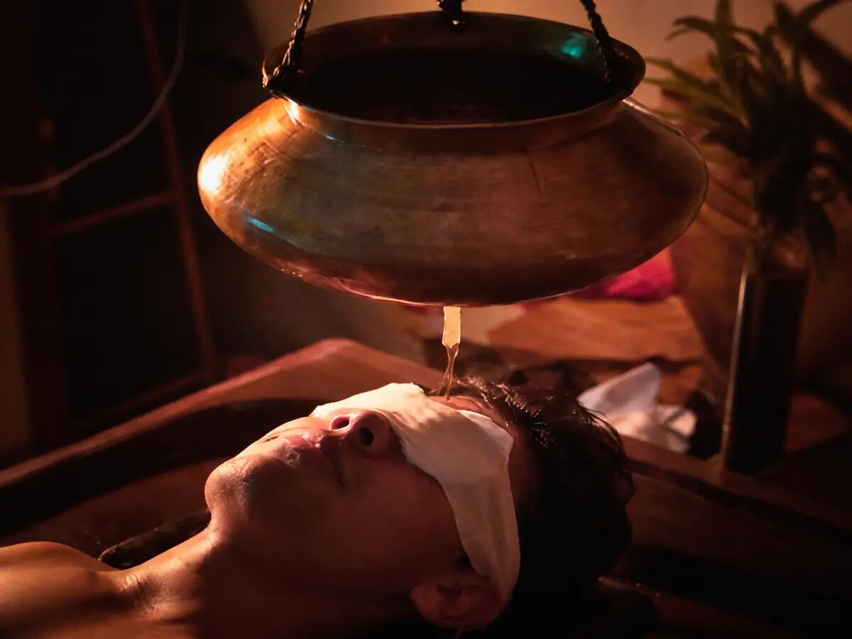 Guest receiving a traditional Shirodhara treatment